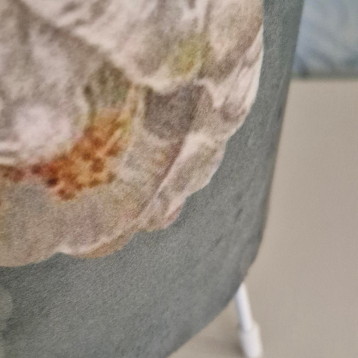 Close-up of a green-gray cylinder lampshade a large abstract floral print in beige, brown, and muted green tones.
